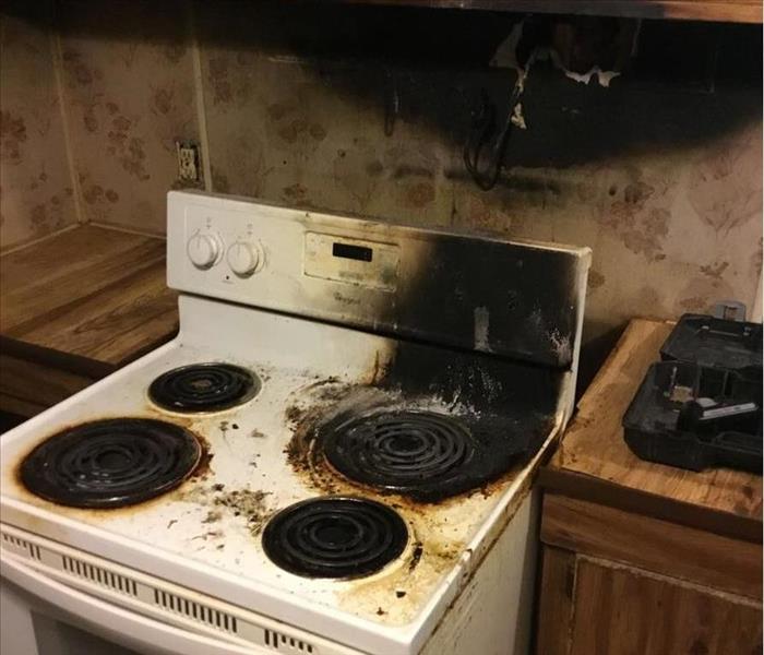 stove top with a burnt burner, burnt cabinets above stove